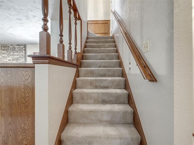 stairs with carpet flooring and a textured wall