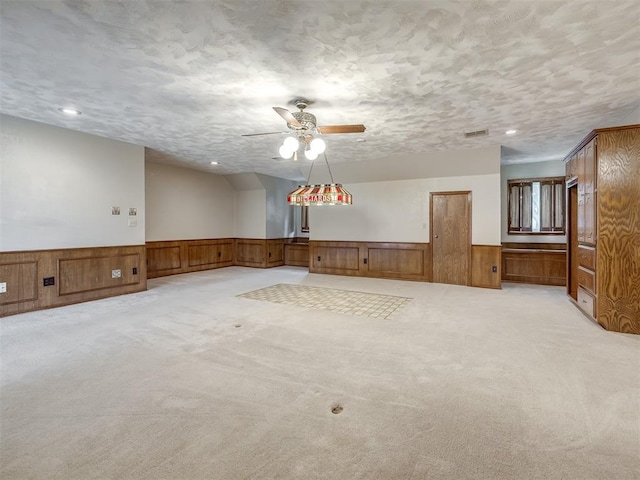 empty room with ceiling fan, light carpet, wainscoting, and visible vents