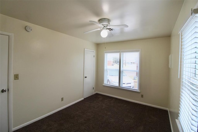 unfurnished room with ceiling fan and dark colored carpet