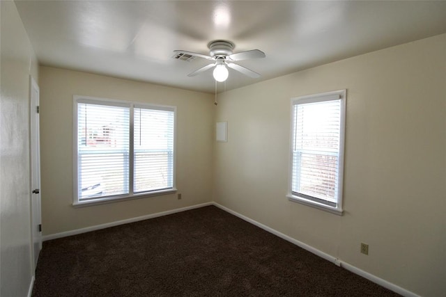 spare room with dark colored carpet and ceiling fan