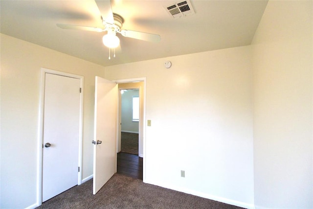 unfurnished bedroom with ceiling fan and dark colored carpet