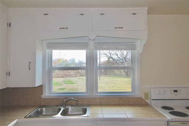 kitchen with tile countertops, sink, white cabinetry, and white stove