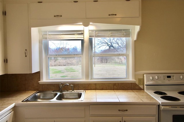 kitchen featuring electric stove, white cabinetry, sink, and tile counters