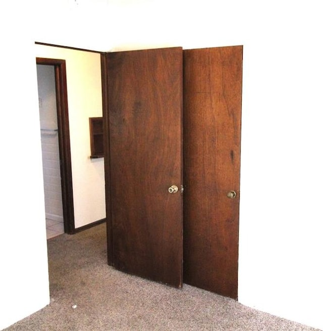 unfurnished bedroom with light colored carpet and a closet