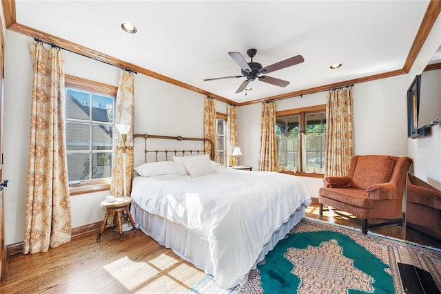 bedroom featuring wood-type flooring, multiple windows, crown molding, and ceiling fan