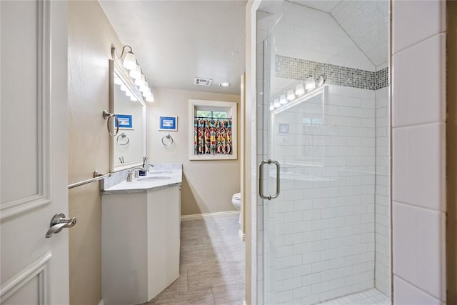 bathroom with vanity, toilet, a shower with shower door, and lofted ceiling