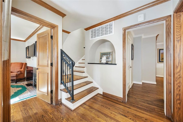 staircase with wood-type flooring and crown molding