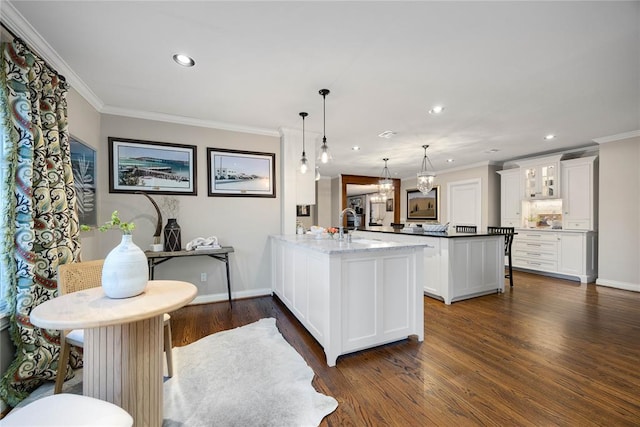 kitchen with kitchen peninsula, dark wood-type flooring, crown molding, decorative light fixtures, and white cabinets