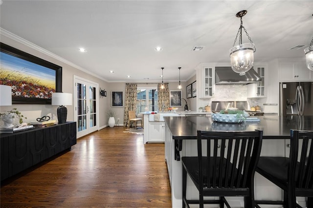 kitchen featuring white cabinetry, dark hardwood / wood-style flooring, range hood, decorative light fixtures, and ornamental molding