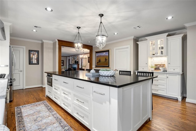 kitchen with a kitchen island, white cabinetry, hanging light fixtures, and dark wood-type flooring