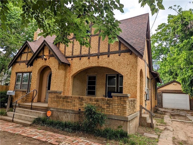 315 W Filmore St, Mangum, OK 73554 - tudor house with an outdoor structure, a shingled roof, concrete driveway, stucco siding, and a garage