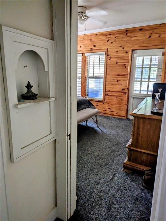 hallway featuring carpet and wooden walls