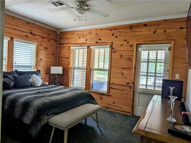 carpeted bedroom featuring ceiling fan, crown molding, and wood walls