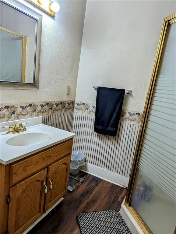 bathroom with hardwood / wood-style floors, vanity, toilet, and a shower with shower door