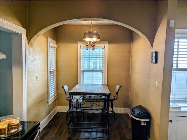 dining room with dark wood-type flooring and an inviting chandelier