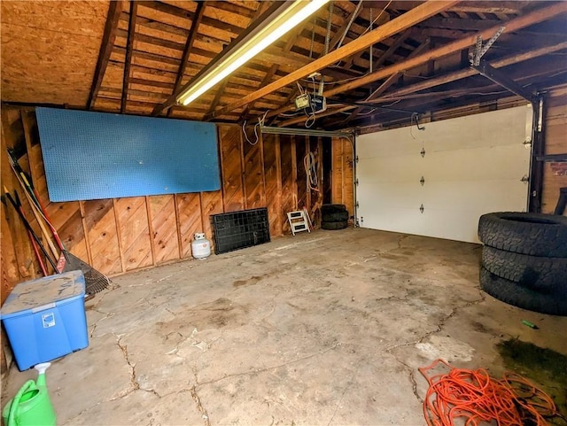 garage featuring a garage door opener and wood walls