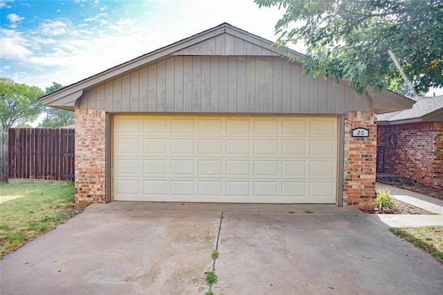 garage featuring concrete driveway and fence