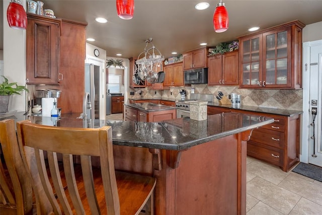 kitchen featuring light tile patterned floors, stainless steel range, tasteful backsplash, a kitchen breakfast bar, and pendant lighting