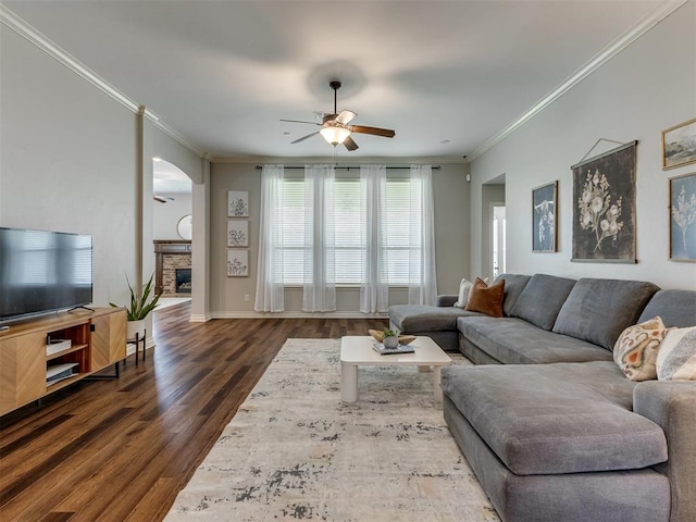 living room with a fireplace, ceiling fan, crown molding, and dark hardwood / wood-style floors