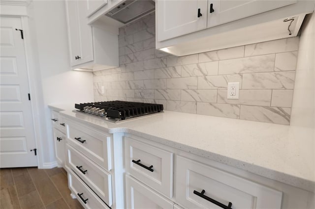 kitchen featuring white cabinetry, light stone countertops, exhaust hood, decorative backsplash, and stainless steel gas cooktop