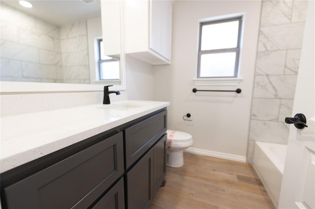 full bathroom featuring vanity, toilet, a healthy amount of sunlight, and hardwood / wood-style floors