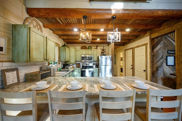 kitchen with sink, kitchen peninsula, decorative light fixtures, a breakfast bar, and appliances with stainless steel finishes