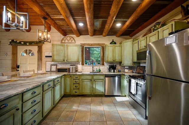 kitchen with sink, stainless steel appliances, wood walls, pendant lighting, and green cabinetry