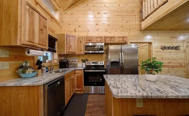 kitchen with light stone countertops, sink, wooden walls, and black appliances