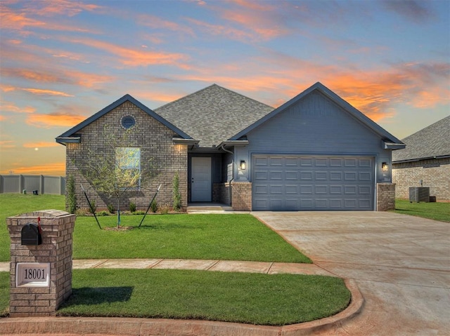 view of front of house featuring a garage, cooling unit, and a lawn