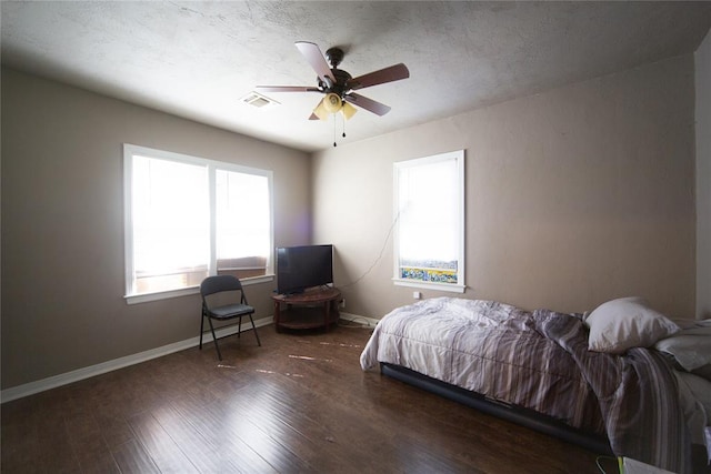 bedroom with a textured ceiling, ceiling fan, and dark hardwood / wood-style floors