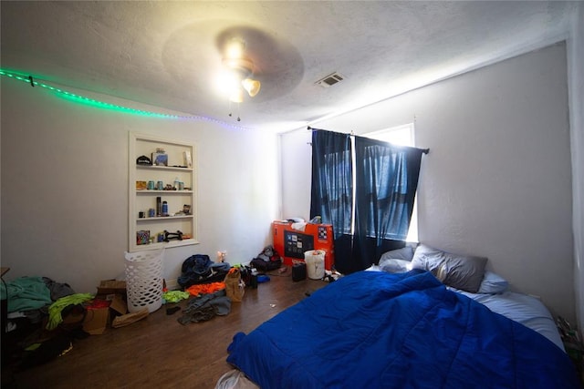 bedroom featuring ceiling fan, wood-type flooring, and a textured ceiling