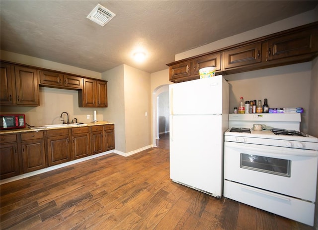 kitchen with a textured ceiling, white appliances, dark hardwood / wood-style floors, and sink