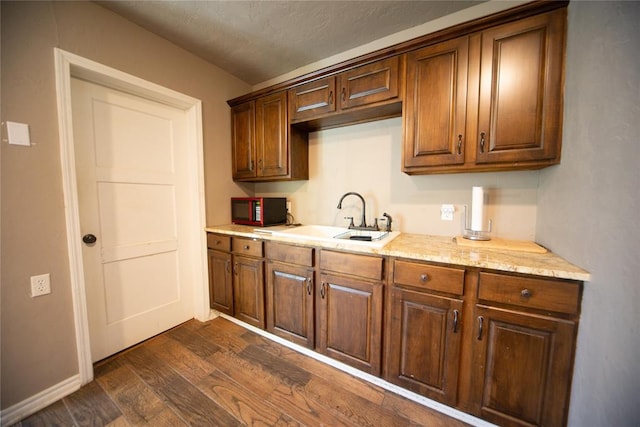 kitchen featuring light stone countertops, sink, dark wood-type flooring, and a textured ceiling