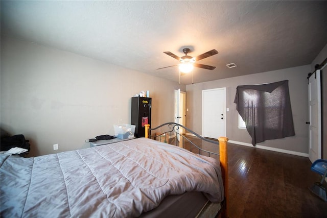 bedroom with a barn door, ceiling fan, a textured ceiling, and hardwood / wood-style flooring