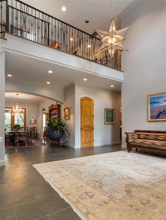 foyer featuring a towering ceiling, crown molding, and an inviting chandelier