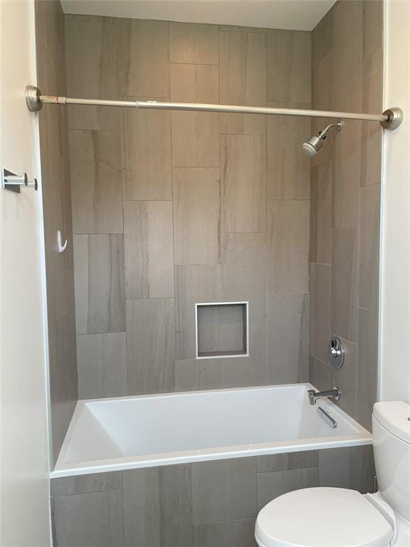 bathroom with tiled shower / bath combo and toilet