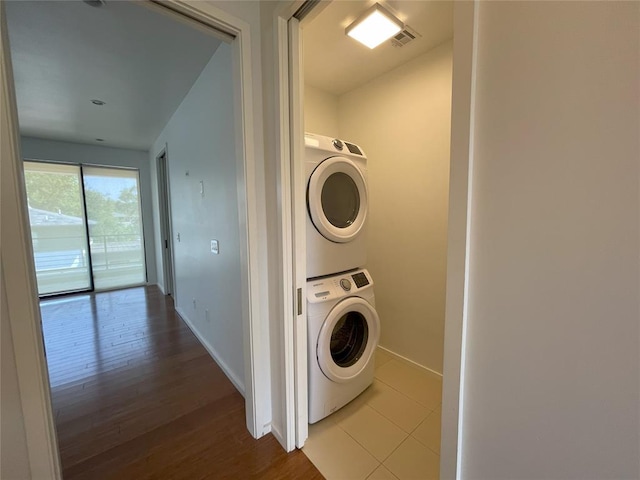 laundry room featuring hardwood / wood-style flooring and stacked washer and clothes dryer