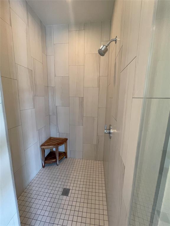 bathroom featuring tile patterned flooring, tiled shower, and tile walls