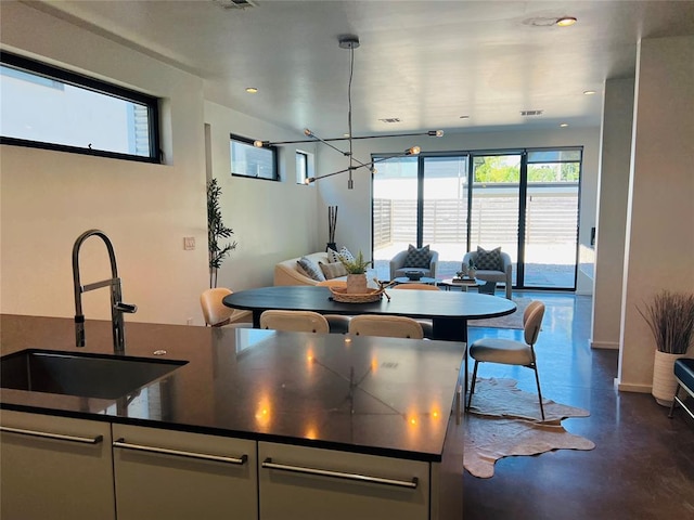 kitchen featuring white cabinetry, sink, a chandelier, and decorative light fixtures