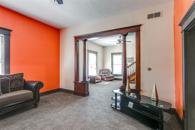 living room with carpet flooring, ceiling fan, and ornate columns