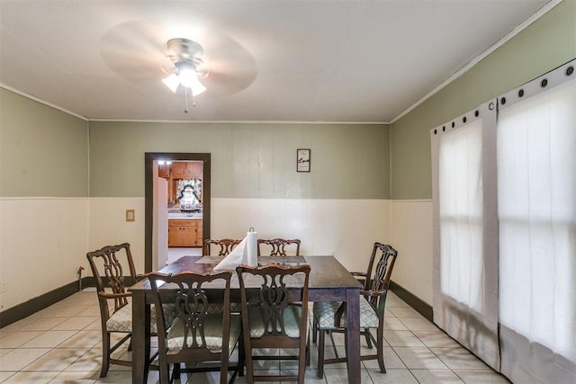 tiled dining space with ceiling fan and ornamental molding