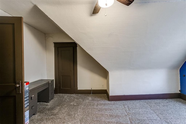 additional living space with dark colored carpet, ceiling fan, and lofted ceiling