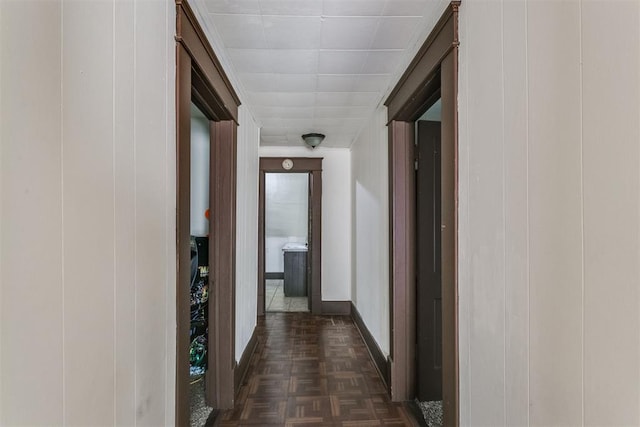 hall featuring dark parquet floors and wood walls