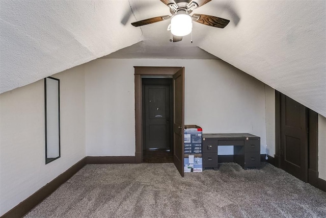 bonus room featuring vaulted ceiling, ceiling fan, a textured ceiling, and dark colored carpet