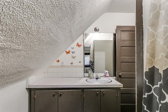 bathroom featuring vanity, a textured ceiling, and vaulted ceiling