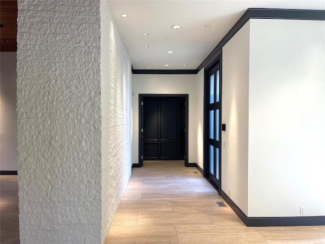 corridor featuring crown molding and light hardwood / wood-style flooring