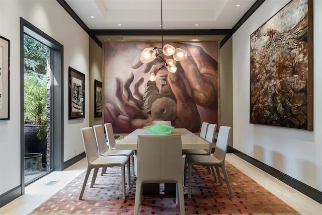 dining space with a tray ceiling, an inviting chandelier, and light hardwood / wood-style floors