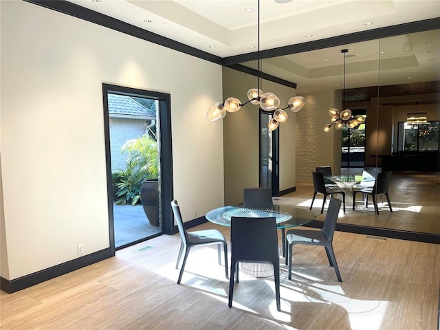 dining space featuring a chandelier, light wood-type flooring, and a tray ceiling