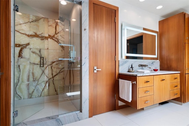 bathroom featuring tile patterned floors, vanity, a shower with shower door, and backsplash