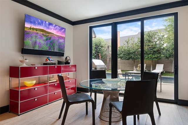 dining area featuring light wood-type flooring, a wealth of natural light, and ornamental molding